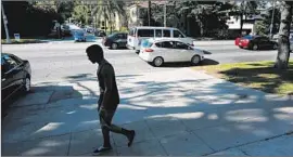  ?? Photog r aphs by Mel Melcon Los Angeles Times ?? A PIECE of tape and a ruler, left, mark the location of a bullet hole through a garage door on the 4000 block of Los Feliz Boulevard where off icers shot Walter William DeLeon. At right, a pedestrian passes the scene of the shooting, which occurred...