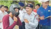  ??  ?? A traffic policeman giving away a helmet to a rider, and educating him on the importance of it