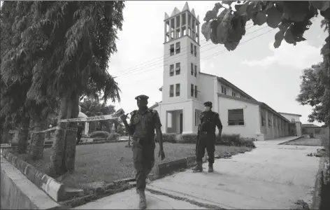  ?? SUNDAY ALAMBA/AP ?? NIGERIAN POLICE OFFICERS targeted worshipers. tape around the St. Francis Catholic church in Owo Nigeria, on Monday a day after an attack that