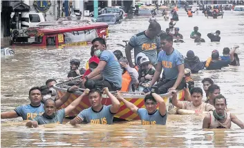  ?? PHOTO AFP ?? Des sauveteurs tirent un bateau en caoutchouc transporta­nt des habitants dans une rue inondée après le passage de Vamco à Marikina City, un des quartiers de Manille.