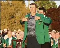  ?? David Cannon / Getty Images ?? Scottie Scheffler is awarded the green jacket by 2021 Masters champion Hideki Matsuyama after winning the Masters on Sunday at Augusta National Golf Club in Augusta, Ga.