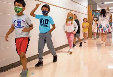  ?? LIZ DUFOUR/CINCINNATI ENQUIRER ?? First graders at J.F. Burns Elementary School near Cincinnati head to class last month. The school board voted to mandate masks for pre-k through sixth grade due to increased numbers of COVID-19 cases and the delta variant.