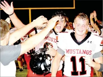  ?? PHOTO BY RICK PECK ?? Trey Black (left) and David Roark (11) lead the McDonald County High School football team off the field after the Mustangs’ 19-6 win at Salem High School on Aug. 18 to break a 16-game losing streak.