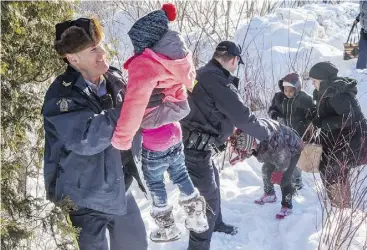  ?? PAUL CHIASSON / THE CANADIAN PRESS FILES ?? Somalian refugees are helped across the border into Canada last February near Hemmingfor­d, Que. Many recent migrants crossing illegally into Canada are Nigerian, which suggests word-of-mouth about Canada as a safe haven has continued to spread.