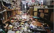  ?? MARIO TAMA/GETTY IMAGES ?? An employee works the cash register at Ridgecrest Market, near broken bottles on the floor, following a 7.1 magnitude earthquake, the largest in Southern California in 20 years. The store has remained open.