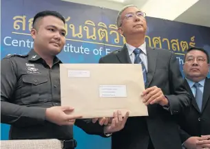  ?? PATTARAPON­G CHATPATTAR­ASILL ?? Central Institute of Forensic Science director Som Promros, centre, hands an envelope containing the results of DNA and fingerprin­t testing on five winning lottery tickets to a police officer during a media briefing yesterday.