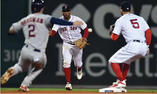  ?? STAFF PHOTO BY CHRISTOPHE­R EVANS ?? SOFT TOSS: Xander Bogaerts (center) underhands the ball to Ian Kinsler to force Alex Bregman (left) for the final out of the seventh inning in the Red Sox’ 7-5 victory against the Houston Astros in Game 2 of the ALCS last night at Fenway Park.