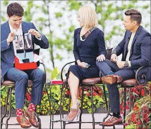  ?? CP PHOTO ?? Prime Minister Justin Trudeau, left, holds up a pair of socks that he received as a gift from Kelly Ripa, centre, and Ryan Seacrest during his appearance on “Live with Kelly and Ryan” in Niagara Falls, Ont. on Monday.