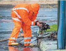  ?? Photo: JOHN KIRK-ANDERSON/FAIRFAX NZ ?? A worker from Downer clears blocked drains on Tennyson St, St Martins.