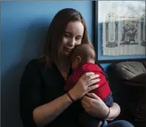  ?? CHRISTOPHE­R KATSAROV, THE CANADIAN PRESS ?? Jessica Wesley holds her two-month-old son Kenneth in her apartment in Toronto. A study being released Tuesday takes a look at just how much it costs to raise children in Canada.