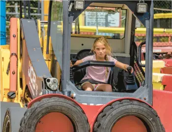  ?? TONY CENICOLA/THE NEW YORK TIMES ?? A young visitor at the controls of a skid steer truck navigates a course Aug. 8 at the constructi­on-themed amusement park.