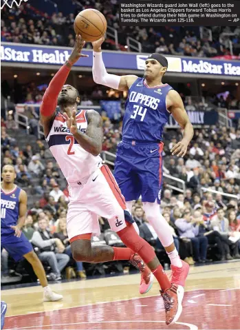  ?? AP ?? Washington Wizards guard John Wall (left) goes to the basket as Los Angeles Clippers forward Tobias Harris tries to defend during their NBA game in Washington on Tuesday. The Wizards won 125-118. —