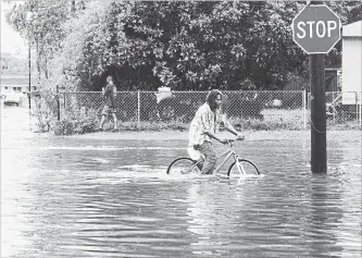  ?? HENRIETTA WILDSMITH, THE SHREVEPORT TIMES THE ASSOCIATED PRESS ?? A man tries to bike through the flooding from the rains of storm Barry in New Iberia, La., Sunday.