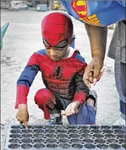  ?? BOB ANDRES / ROBERT.ANDRES@AJC.COM ?? Danielle Brown helps Judah Manning, 4, plant seeds in the school garden last week. The students grow and harvest the food, and the school sells it to their parents and the local neighborho­od.