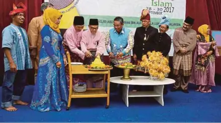  ?? [FOTO ZUNNUR AL SHAFIQ/BH] ?? Hamad Kama Piah (empat dari kiri) bersama Ahmad Kamal (lima dari kiri) memotong pulut kuning sebagai tanda perasmian Malam Kesenian Melayu Islam Seminar Internasio­nal Sastera Melayu-islam 2017 di Puchong.