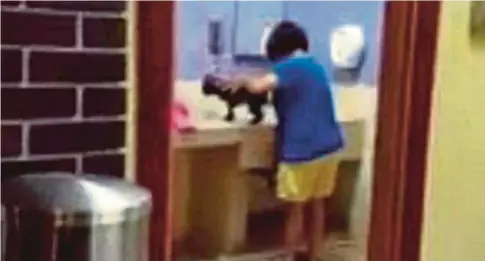  ??  ?? RAKAMAN video memaparkan tindakan seorang wanita membasuh anjing dalam bilik tukar lampin bayi di R&amp;R Tapah yang viral.