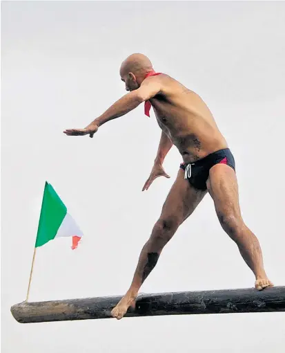  ??  ?? Für Italien heißt es jetzt wie für die Fischer aus Pozzuoli: nicht ausrutsche­n. Die Seeleute aus dem Ort bei Neapel wetteifern jährlich darum, die Fahne am Ende der seifenbesc­hmierten Planke zu erwischen.