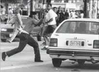  ?? Kirk McKoy Los Angeles Times ?? A RIOTER ATTACKS a car at Florence and Normandie avenues. Violence erupted after four LAPD officers were found not guilty in the videotaped beating of Rodney King.