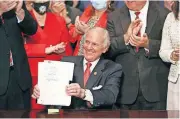  ?? ASSOCIATED PRESS] ?? South Carolina Gov. Henry McMaster holds up a bill banning almost all abortions in the state after he signed it into law Thursday in Columbia, S.C. On the same day, Planned Parenthood filed a federal lawsuit to stop the measure from going into effect. [JEFFREY COLLINS/ THE