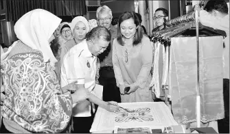  ??  ?? Naroden tries his hands at batik-painting at a booth in an exhibition on entreprene­urship, set up in conjunctio­n with the seminar.