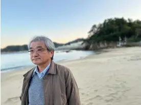  ?? Photograph: Justin McCurry/The Guardian ?? Tsuyoshi Suda, an anti-nuclear campaigner, with Onagawa nuclear power plant in the background. Suda says Japan’s plans to invest in nuclear power is ‘a form of self-destructio­n’.