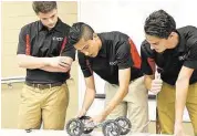  ?? CFISD ?? Cypress Lakes High School seniors Nicholas Rechner, left, Abel Gallegos and Hayden Drollett display how their integrated automotive lifting jack works for the guests at the Project Lead The Way senior engineerin­g design presentati­on on May 13.