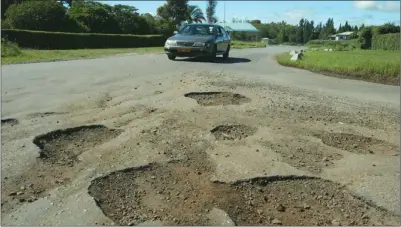  ?? ?? A vehicle approaches a pothole-ridden part of a road in Harare, Zimbabwe