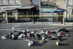  ?? JOHN MINCHILLO — THE ASSOCIATED PRESS ?? Shoes are piled outside the scene of a mass shooting including Ned Peppers bar Sunday in Dayton.