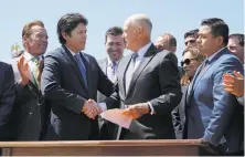  ?? Santiago Mejia / The Chronicle ?? State Senate President Pro Tem Kevin de León and Gov. Jerry Brown (center) shake hands after Brown signed AB398, a bill extending California’s cap-and-trade system.