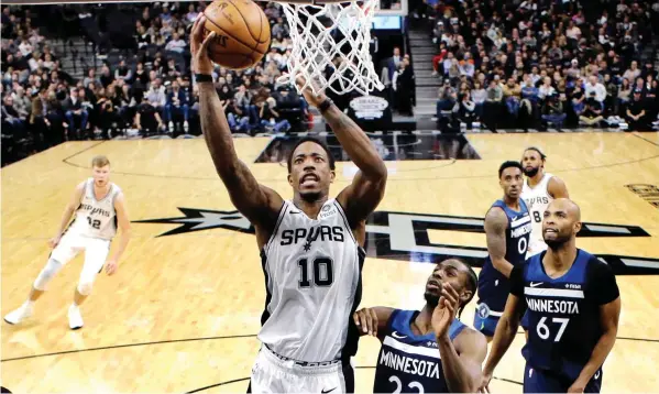  ??  ?? San Antonio Spurs guard DeMar DeRozan scores past Minnesota Timberwolv­es guard Andrew Wiggins during the second half of an NBA basketball game in San Antonio. San Antonio won 112-108. ASSOCIATED PRESS