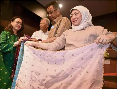  ?? — Bernama ?? National treasure: Nancy holding up a woven shawl during her visit to the Songket Gallery. according to her, the review of the MM2H programme will be completed by year-end.