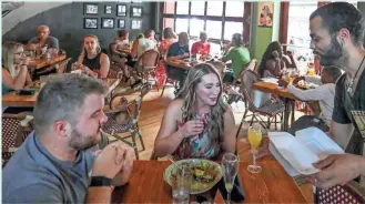  ?? EBONY COX / MILWAUKEE JOURNAL SENTINEL ?? Clay Prather serves Kathleen Bailey and Kyle Sheppard at Cafe Benelux. These days, tables are in demand, but workers can be in short supply.