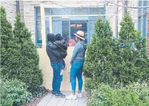  ?? ROSIE DIMANNO TORONTO STAR ?? John and Shawna and their three-year-old son visit John’s mother at the Amica seniors residence on Avenue Road. A box constructe­d using Plexiglas allows residents to safely receive visitors.