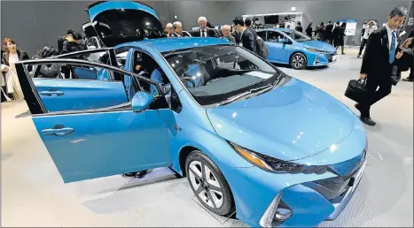  ??  ?? PLUG-IN POWER: Journalist­s take a closer look at the redesigned Toyota Motor Prius PHV (plug-in hybrid vehicle) during a media conference in Tokyo yesterday