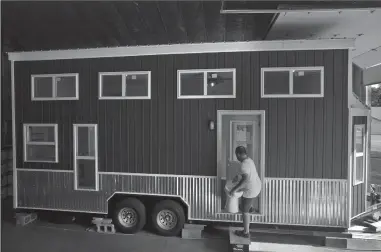  ?? TRIBUNE NEWS SERVICE ?? Mark Mitchell, co-owner of Mini Mansions Tiny Home Builders, installs a toilet in a 350-square-foot loft home in his St. Peters workshop.