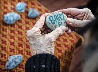  ?? PHOTOS BY JIM WEBER THE NEW MEXICAN ?? RIGHT: Linda Osborne picks up and holds each rock inscribed with the name of a homeless person who died in Santa Fe this year.