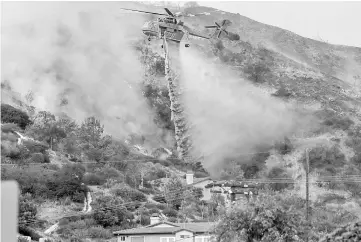  ??  ?? Water is dropped above homes in Sun Valley during the La Tuna Canyon fire over Burbank. — Reuters photo