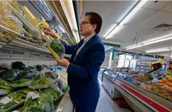  ?? PAT GREENHOUSE/GLOBE STAFF ?? Lowell City Councilor Paul Ratha Yem, seen shopping in New Pailin Market, says Haitian migrants, like Cambodians before them, seek to build new lives.