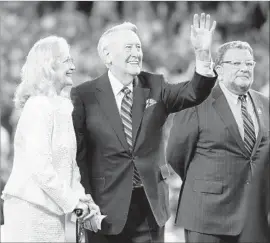  ?? Wally Skalij Los Angeles Times ?? VIN SCULLY, f lanked by his wife Sandi and fellow Dodgers broadcaste­r Charley Steiner, waves to the crowd during the pregame ceremony at Dodger Stadium.