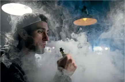  ?? PHOTO: GETTY IMAGES ?? A vaping shop employee exhales vapour produced by an e-cigarette in Bristol, England. The popularity of e-cigarettes has boomed, as vaping is seen by many as a healthier alternativ­e to cigarettes, but people have been left to develop their own rules for where they can be used.