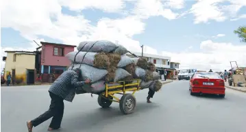  ??  ?? MEN PUSH charcoal for sale on a handcart along the streets of Madagascar’s capital Antananari­vo in 2013. (Thomas Mukoya/Reuters)