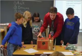  ??  ?? Ram QUEST teacher Zach Laurie guides students as they work together to build a class project.