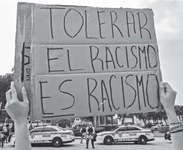  ?? CARL JUSTE cjuste@miamiheral­d.com ?? A Black Lives Matter protester holds her sign as Trump supporters and a Black Lives Matter group intersect at a distance in Miami Lakes on June 28.