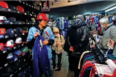  ?? HIRO KOMAE ASSOCIATED PRESS FILE PHOTO ?? A store clerk, left, helps a customer choose items related to Shohei Ohtani of the Los Angeles Dodgers in February at Selection, a sporting goods store in Shinjuku district of Tokyo.