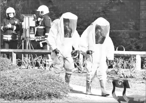  ?? AFP photo ?? File photo shows members of the fire brigade in green biohazard encapsulat­ed suits working to re-attach the tent at the scene of a nerve agent attack at The Maltings shopping centre in Salisbury, southern England.—