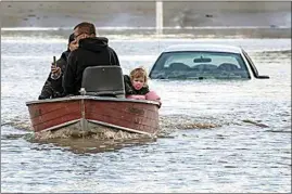  ?? DARRYL DYCK / THE CANADIAN PRESS VIA AP ?? People, including a toddler, and a dog who were stranded by high water due to flooding are rescued by a volunteer operating a boat in Abbotsford, British Columbia, on Tuesday.