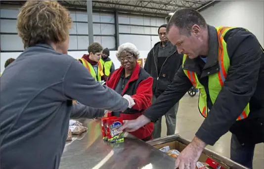  ?? Jessie Wardarski/Post-Gazette ?? Food bank volunteer Barb Trusilo, left, of Churchill takes a food ticket from Rosetta White of Dravosburg, third from right, and her husband Jon White of Dravosburg, second from right, as they're helped by food bank volunteer Andy Henry of Moon.