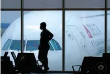  ?? AP PHOTO/CHARLIE RIEDEL ?? A passenger waits for a Delta Airlines flight in 2021 at Hartsfield­Jackson Internatio­nal Airport in Atlanta.