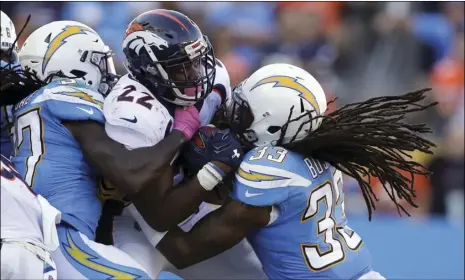  ?? PHOTO/JAE C. HONG ?? Denver Broncos running back C.J. Anderson (middle) is tackled by Los Angeles Chargers free safety Tre Boston (right) and strong safety Jahleel Addae during the second half of an NFL football game on Sunday in Carson. AP