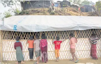 ??  ?? FROM THE OUTSIDE IN: Rohingya refugee children look at other children attending classes in a school at Balukhali refugee camp near Cox’s Bazar, Bangladesh.